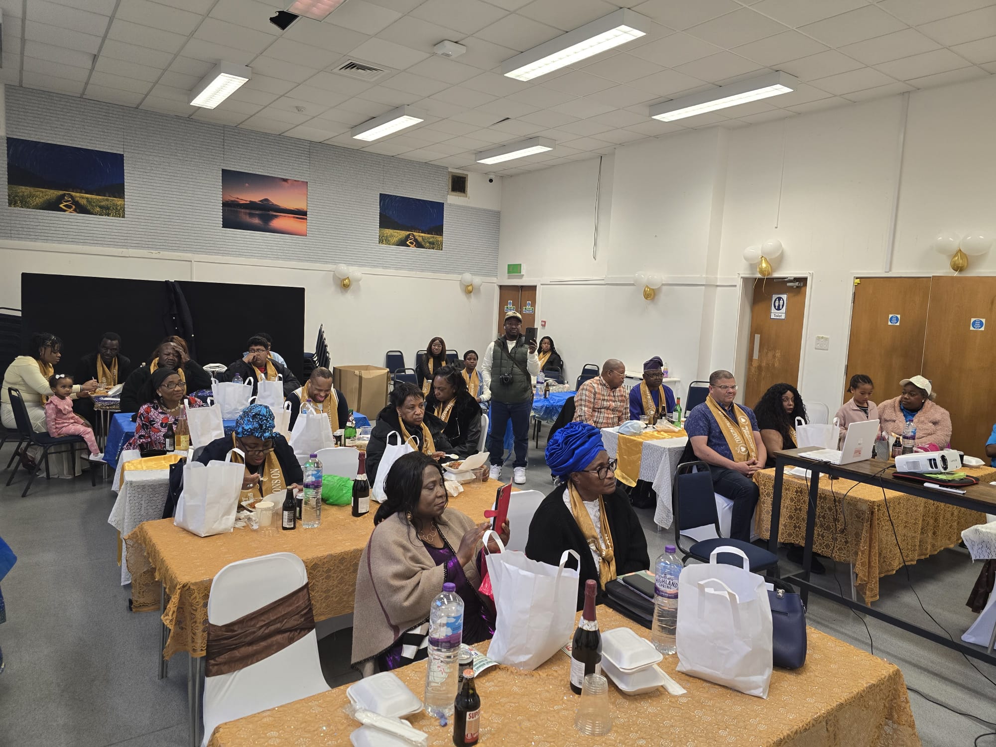 Community members celebrating together at decorated tables with gold accents