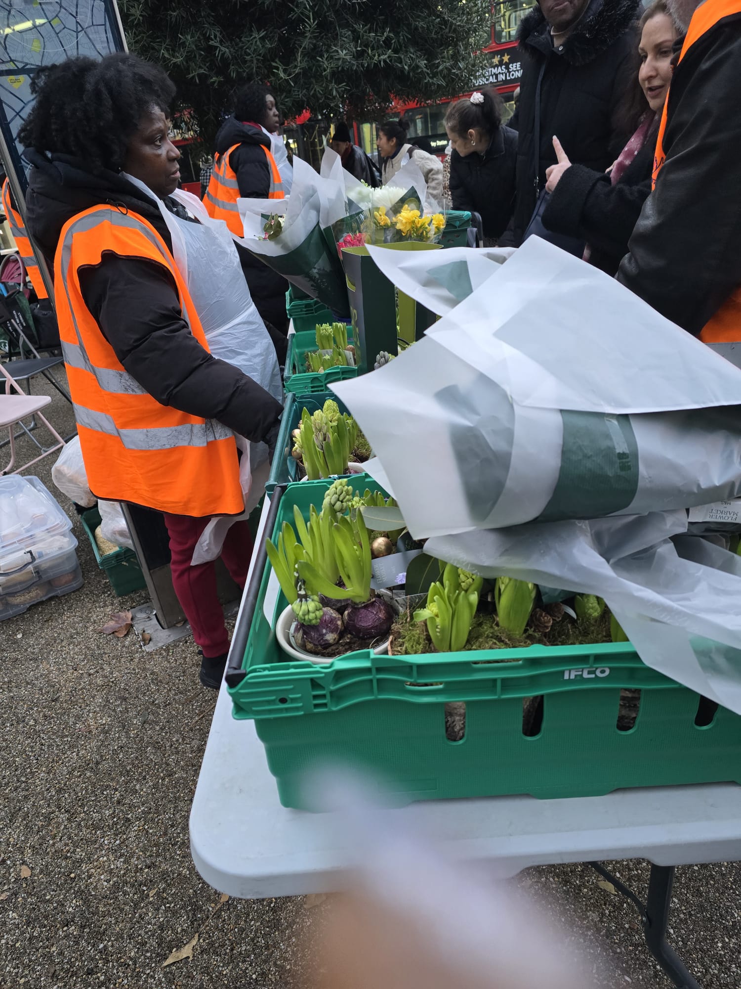 December 2025 Food Distribution - Volunteer distributing fresh produce and flowers to community