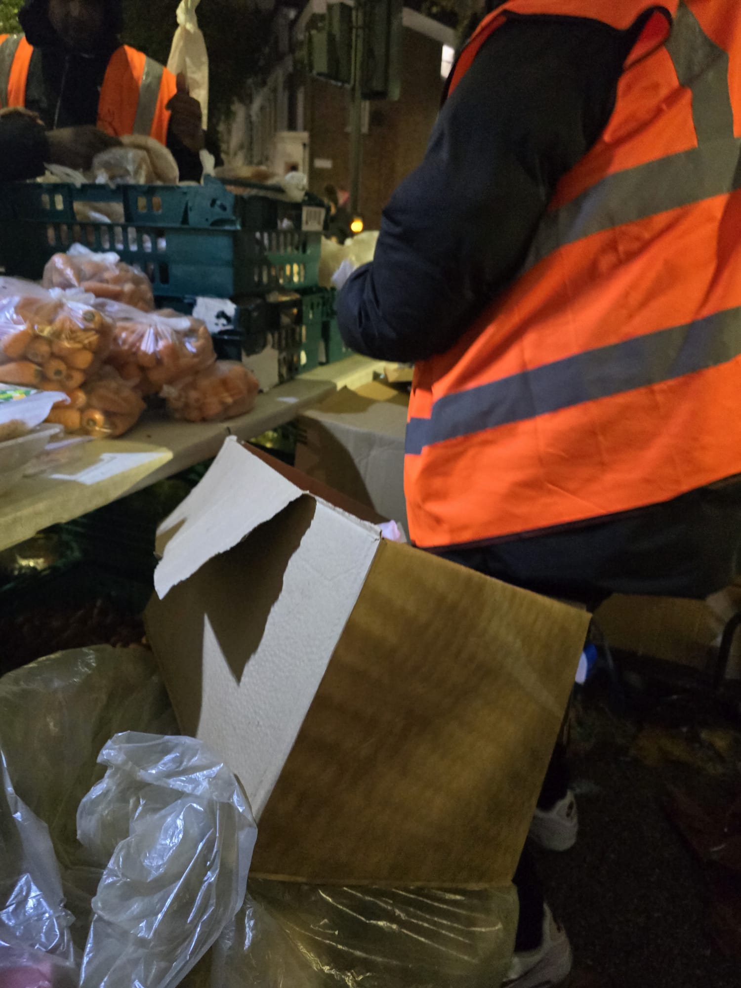 Volunteer in orange safety vest packing food parcels for distribution